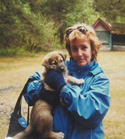 Beverly W. on vacation in Alaska, holding a sled dog puppy